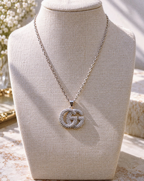 THE CELESTE CRYSTAL NECKLACE on a cream linen bust in warm sunlight