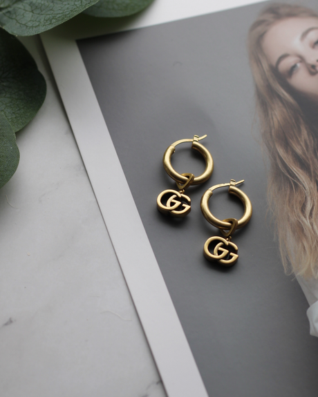 THE GOLDEN ERA HOOPS, photographed pair of gold-tone hoops with vintage letterform charms